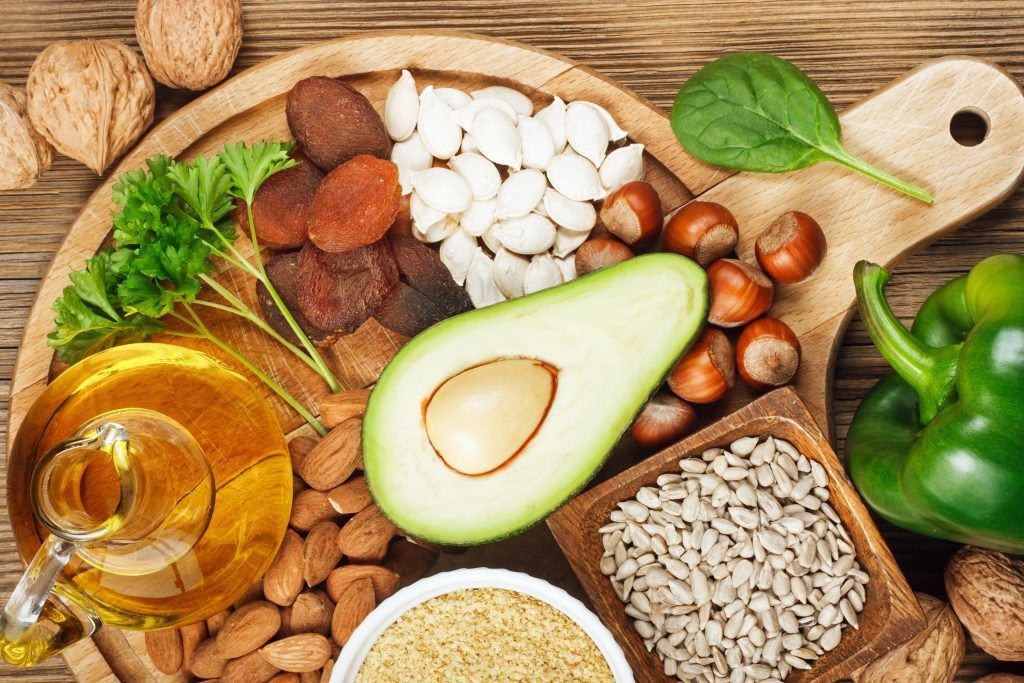 Foods rich in vitamin E including wheat germ oil, dried wheat germ, dried apricots, hazelnuts, almonds, parsley leaves, avocado, walnuts, pumpkin seeds, sunflower seeds, spinach and bell pepper