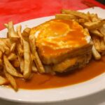 Francesinha, a hearty Portuguese sandwich layered with meats, cheese, and a rich tomato beer sauce, a signature food in Portugal