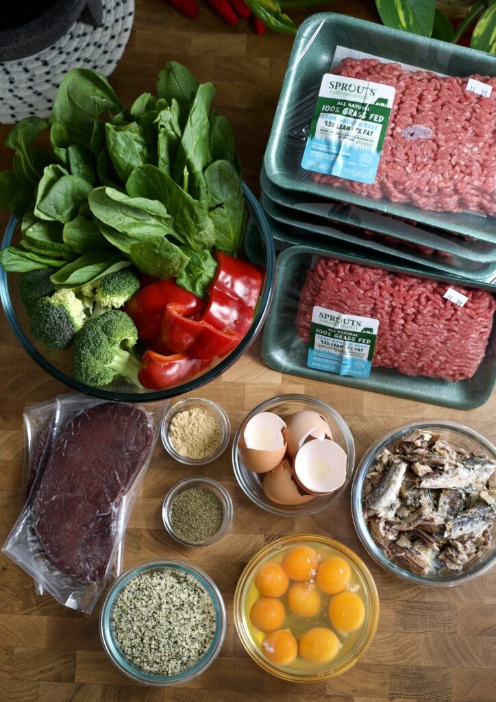 Fresh ingredients for homemade dog food, including ground beef, vegetables, eggs, and supplements.