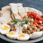 Ful Medames, a staple Egyptian breakfast and street food, featuring mashed fava beans with olive oil and garnishes.