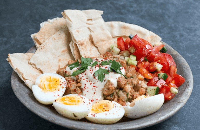 Ful Medames, a staple Egyptian breakfast and street food, featuring mashed fava beans with olive oil and garnishes.