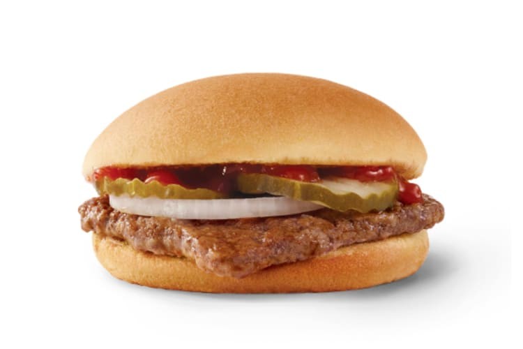 Hamburger topped with pickles, onion, ketchup and mustard on a bun.