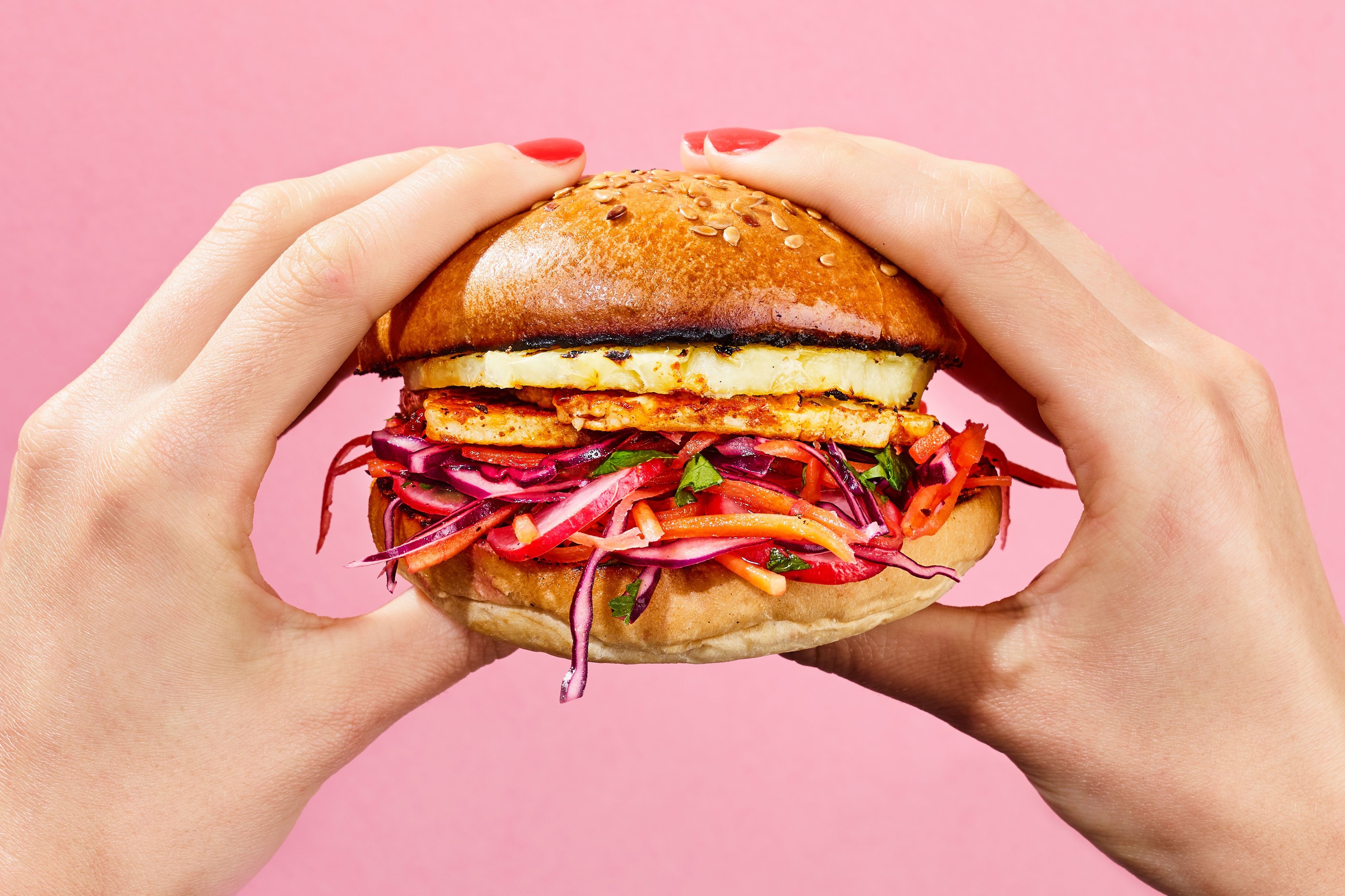 Hands holding halloumi burger with mixed veg