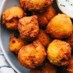 Hush Puppies on a plate with a side of tartar sauce.