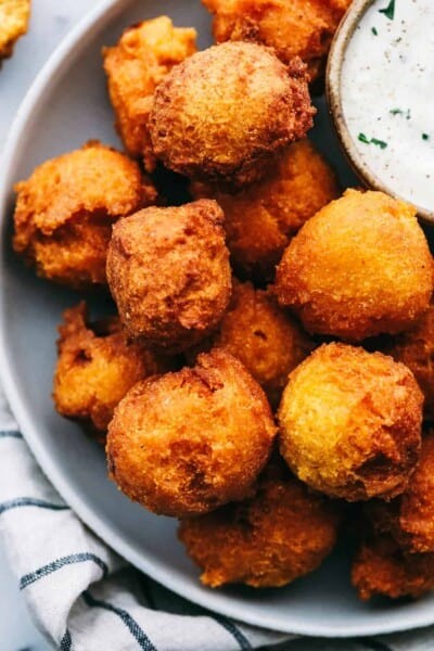 Hush Puppies on a plate with a side of tartar sauce.