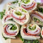 Italian pinwheel appetizers arranged on a wooden cutting board, showcasing their colorful layers and inviting presentation.