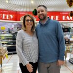 Joanne Greeley Graham and her son, Justin Graham, stand proudly in the bakery section of Geresbeck's Food Market in Pasadena, showcasing eclairs and marshmallow doughnuts.