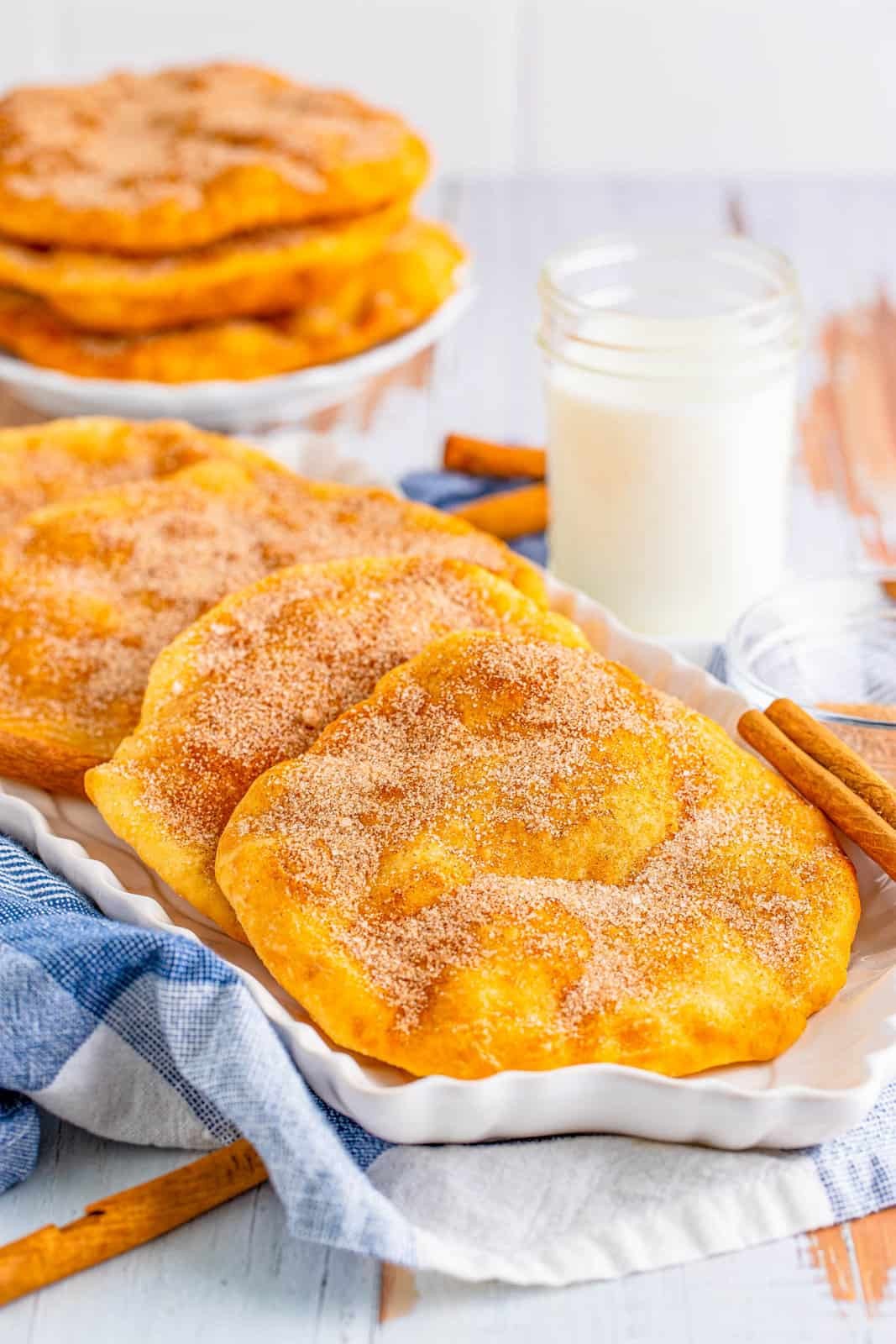 Layered Elephant Ears Recipe on white platter with milk in back with plate with more Elephant Ears stacked.