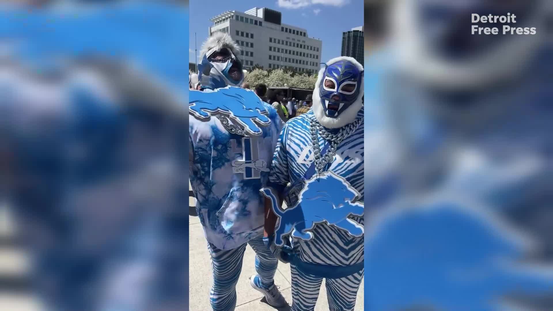 NFL Draft attendees entering through security, with downtown Detroit buildings in the background