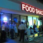 Outside view of Little Moir's Food Shack, Jupiter, FL, showing people waiting and the restaurant's signage.