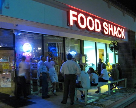 Outside view of Little Moir's Food Shack, Jupiter, FL, showing people waiting and the restaurant's signage.