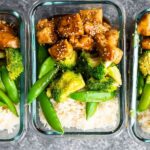 Overhead shot of Honey Sesame Chicken Lunch Bowls neatly packed in meal prep containers, showcasing an easy lunch idea for busy individuals.