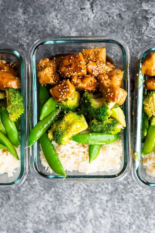 Overhead shot of Honey Sesame Chicken Lunch Bowls neatly packed in meal prep containers, showcasing an easy lunch idea for busy individuals.