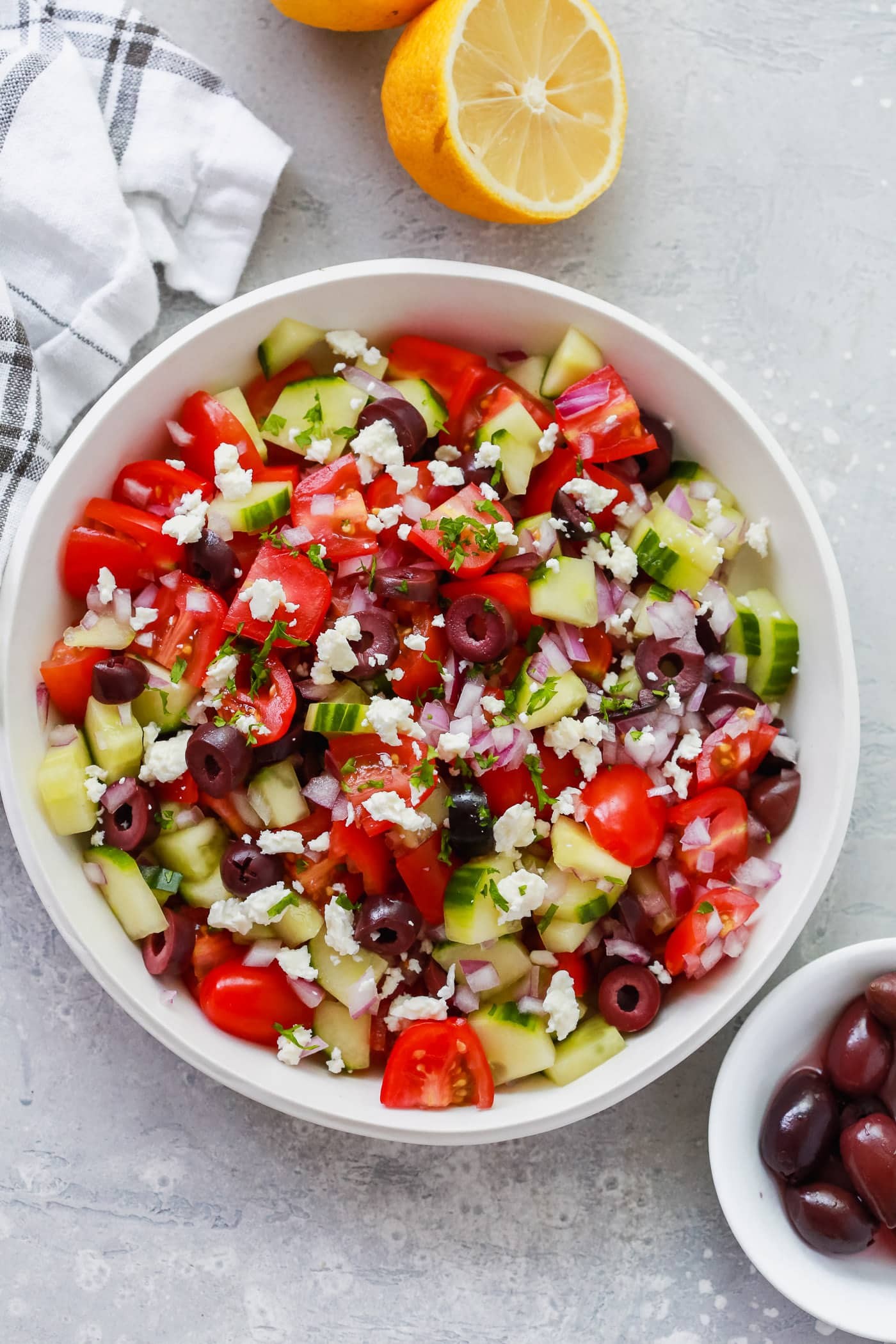 Overhead view of a vibrant Mediterranean Salad in a white bowl, showcasing fresh vegetables and a light dressing