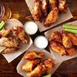 Overhead view of four orders of chicken wings with sauces