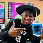 Person holding up blue Slurpee inside 7-Eleven s