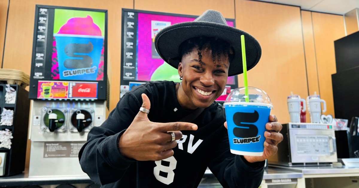 Person holding up blue Slurpee inside 7-Eleven s