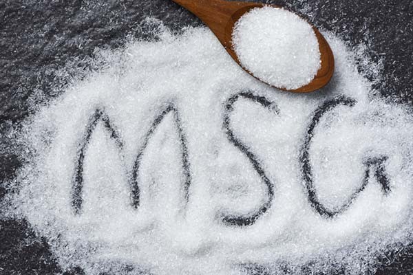 Pile of MSG crystals with wooden scoop and MSG letters drawn in crystals