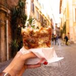 Pizza al taglio, a popular italian street food, displayed in a Rome shop, showcasing various toppings.