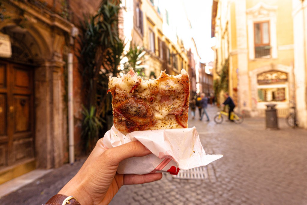 Pizza al taglio, a popular italian street food, displayed in a Rome shop, showcasing various toppings.