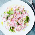 Plate of thinly sliced radishes with salsa verde dressing