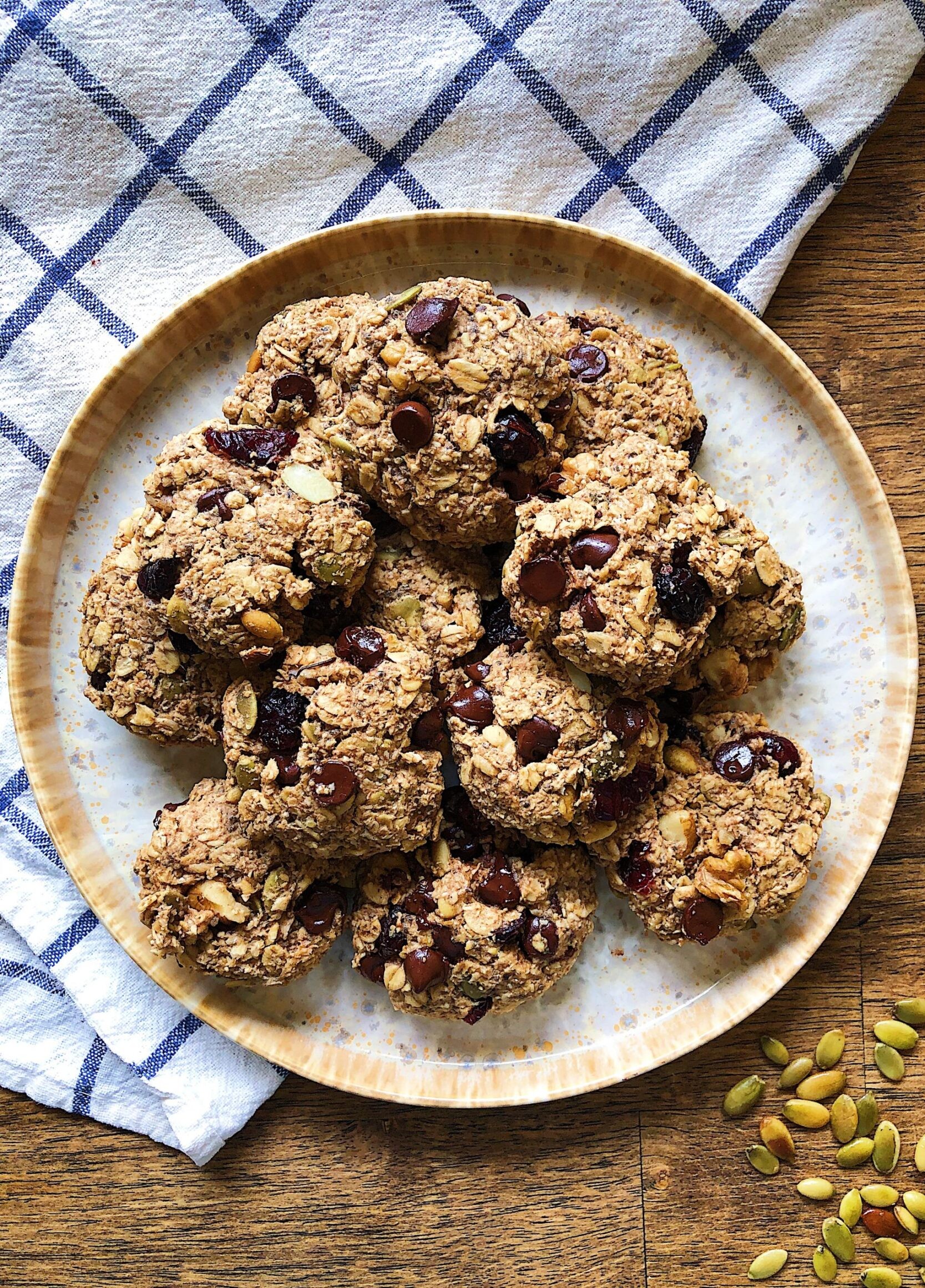 Plate with breakfast cookies filled with oats, nuts and chocolate chips, with a white and blue cloth in the background.