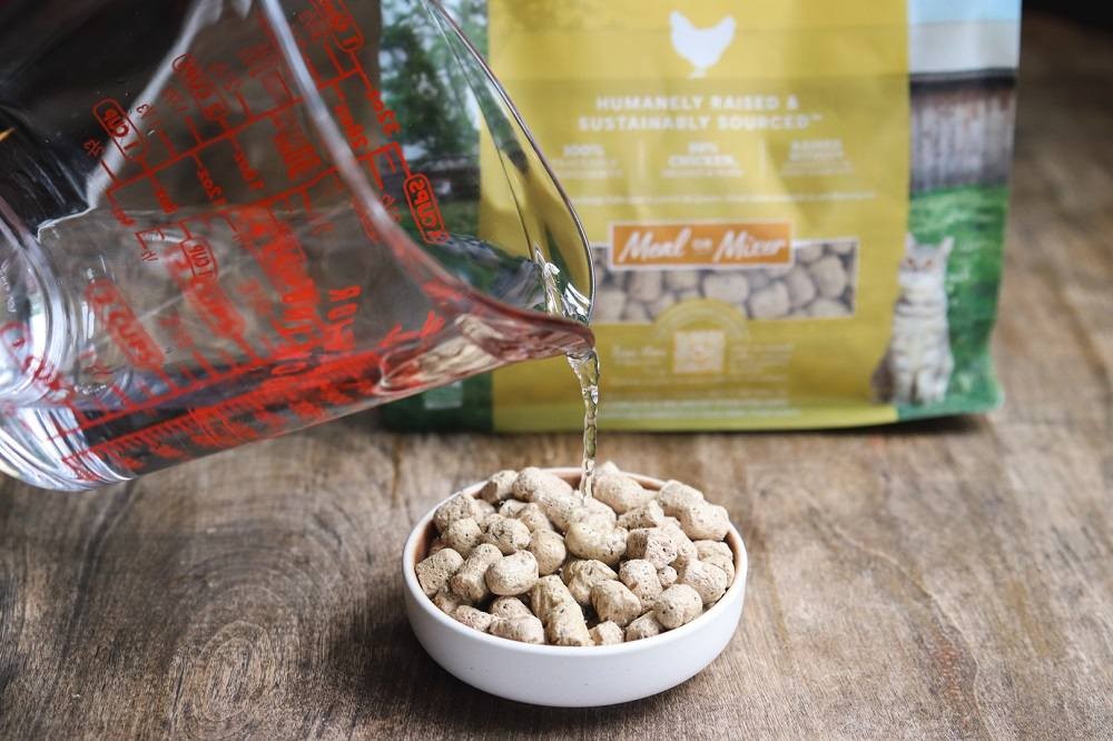 Pouring Open Farm Freeze Dried Raw Harvest Chicken Cat Food into a bowl