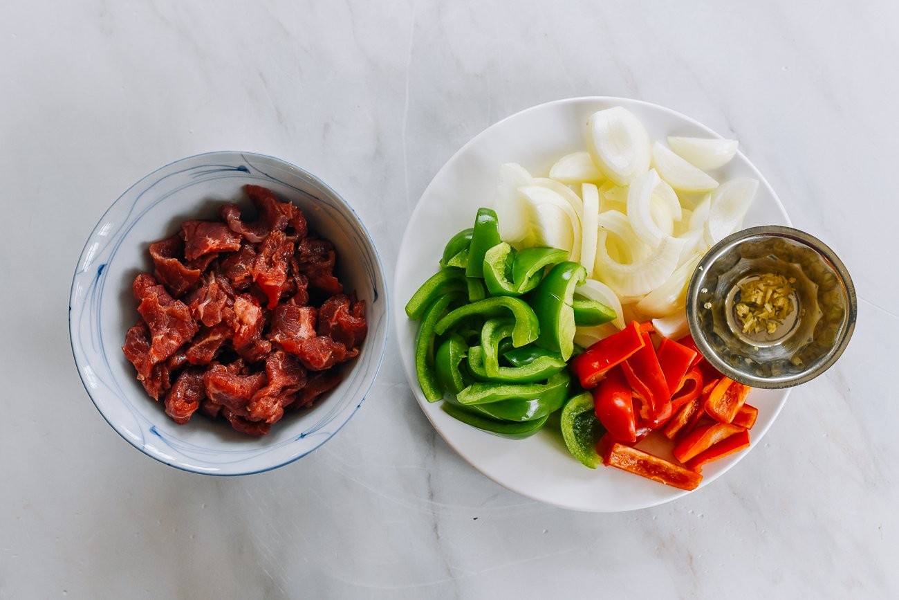 Preparing marinated beef, bell peppers, and onions for pepper steak