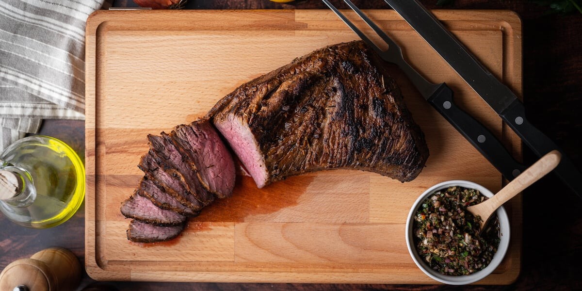 Sizzling ribeye steak on the grill with rosemary sprigs