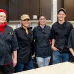 Smiling Whole Foods Co-op team members in chef uniforms.