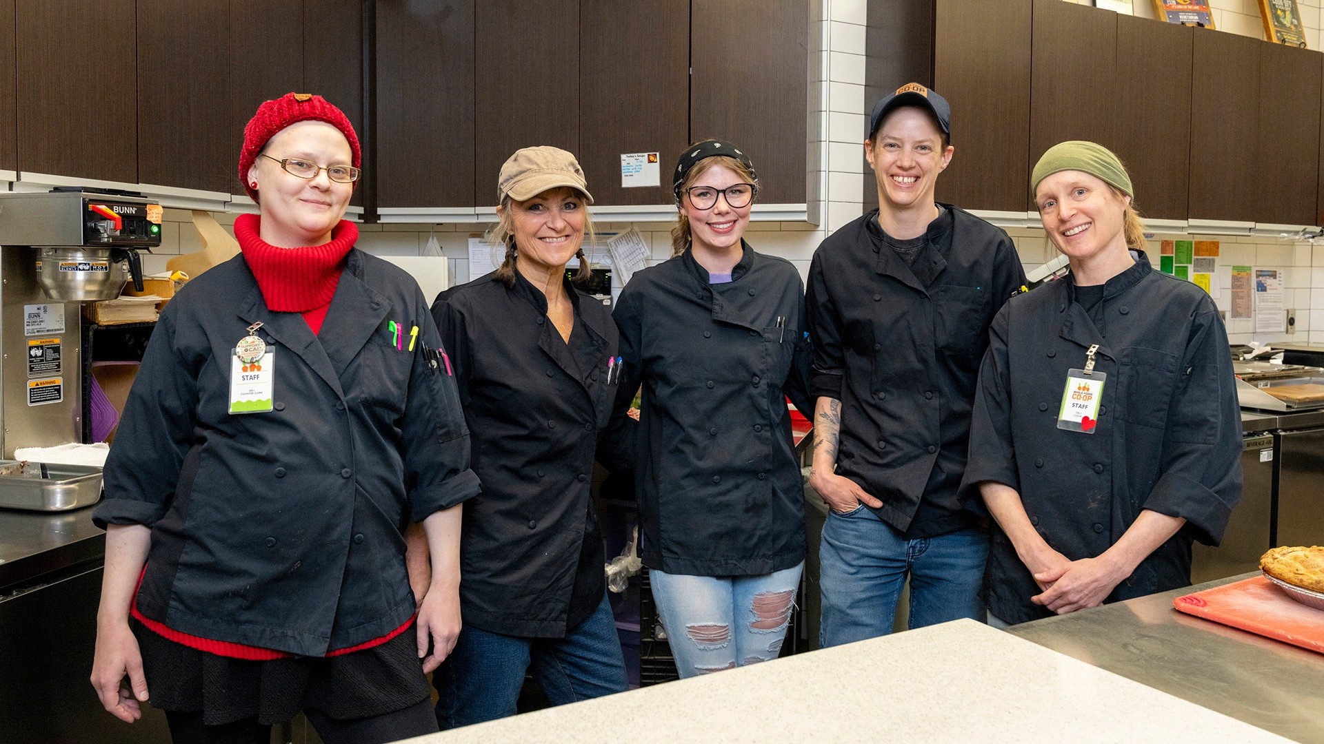 Smiling Whole Foods Co-op team members in chef uniforms.