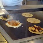 Tacos being grilled with cheese at Puesto Mexican Street Food in La Jolla