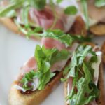 This Brie, Fig, and Prosciutto Crostini recipe makes a flavorful and easy appetizer. #appetizer #crostini #fig #arugula #brie #prosciutto