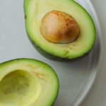 two avocados are cut in half on a white plate .