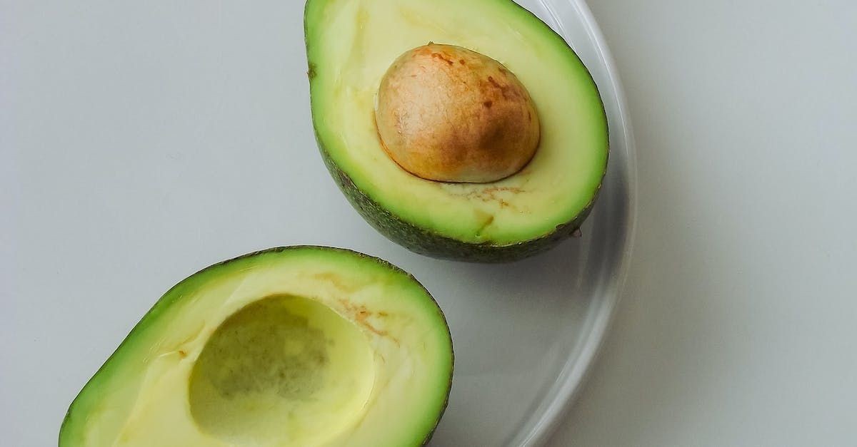 two avocados are cut in half on a white plate .