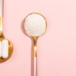 Two spoons, one with collagen powder and one with collagen supplements, set on a pink background