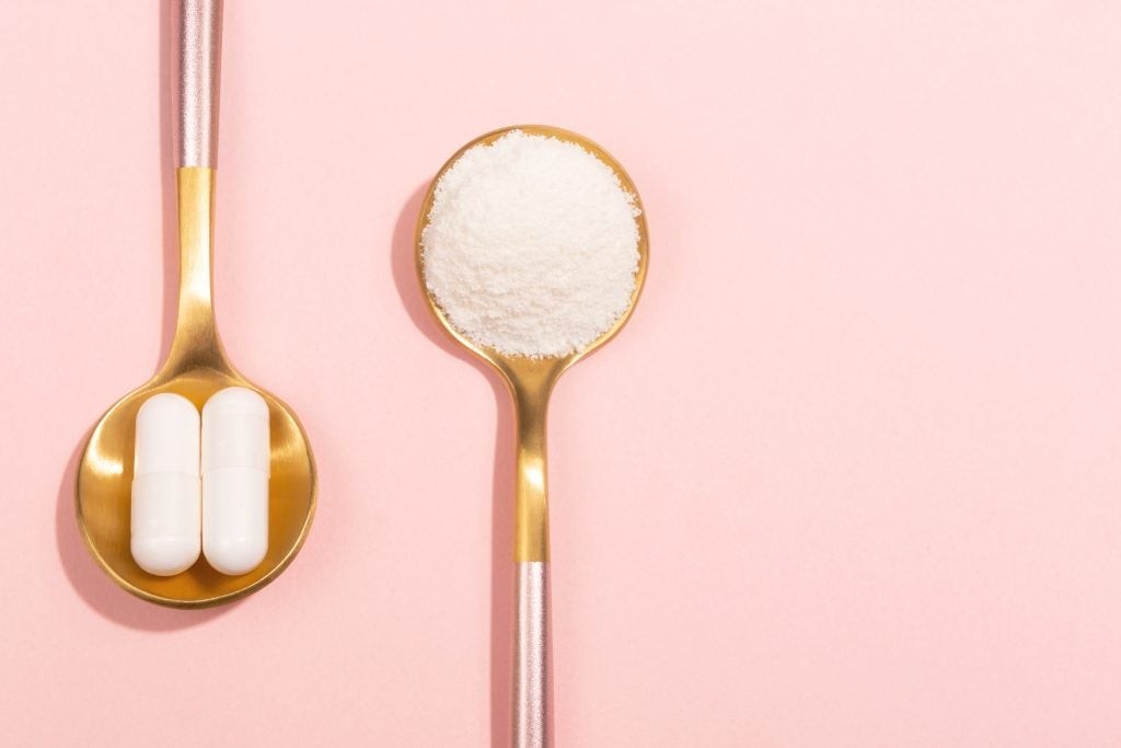 Two spoons, one with collagen powder and one with collagen supplements, set on a pink background