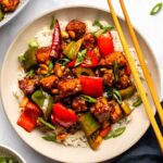 Vegan Kung pao tofu served over white rice and garnished with green onions