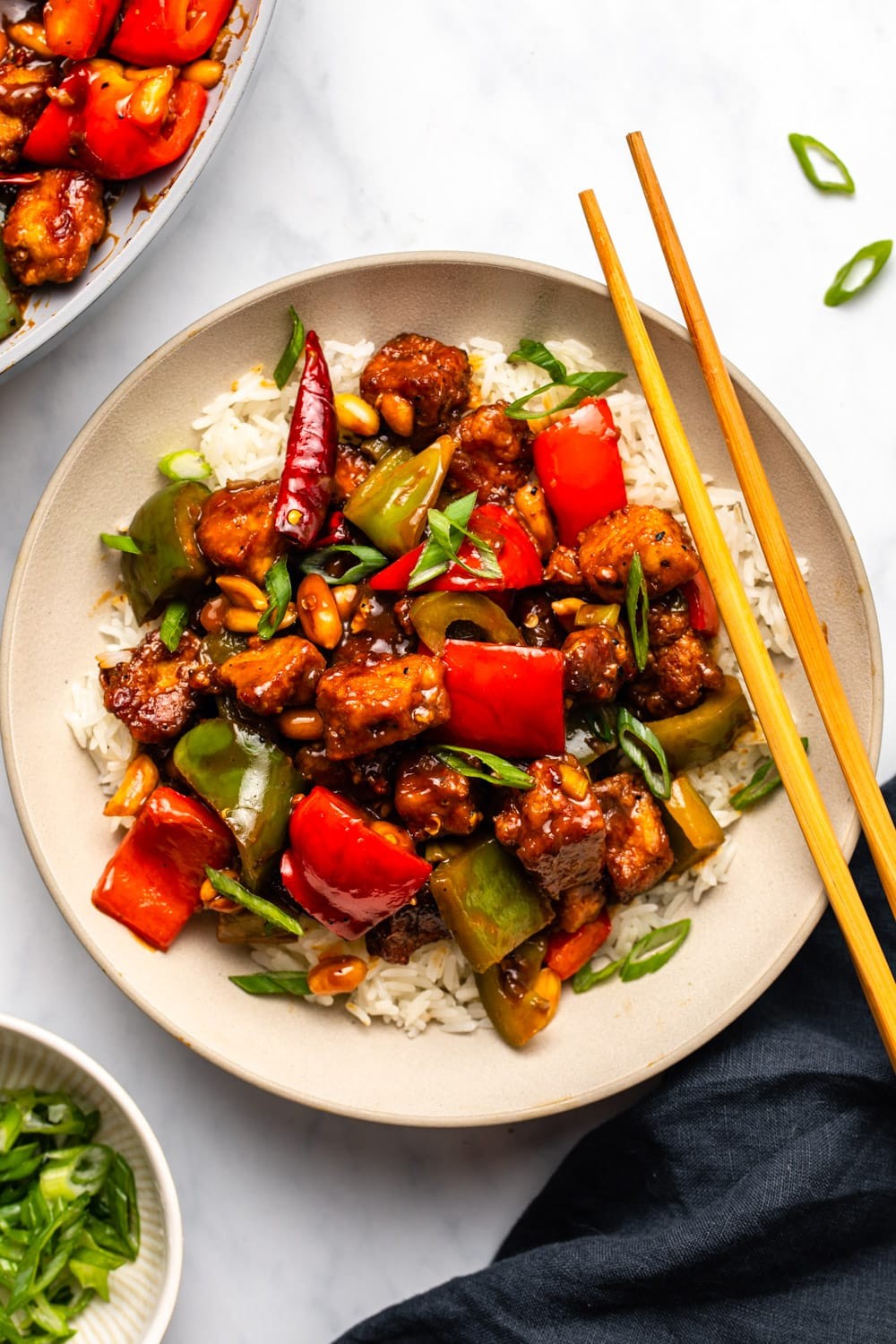 Vegan Kung pao tofu served over white rice and garnished with green onions