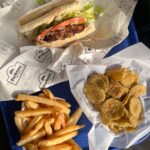 Vegan po'boy sandwich with fried pickles and fries