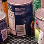 Warning signs of unsafe canned food include dents, cracks, and bulging, indicating potential botulism risk.