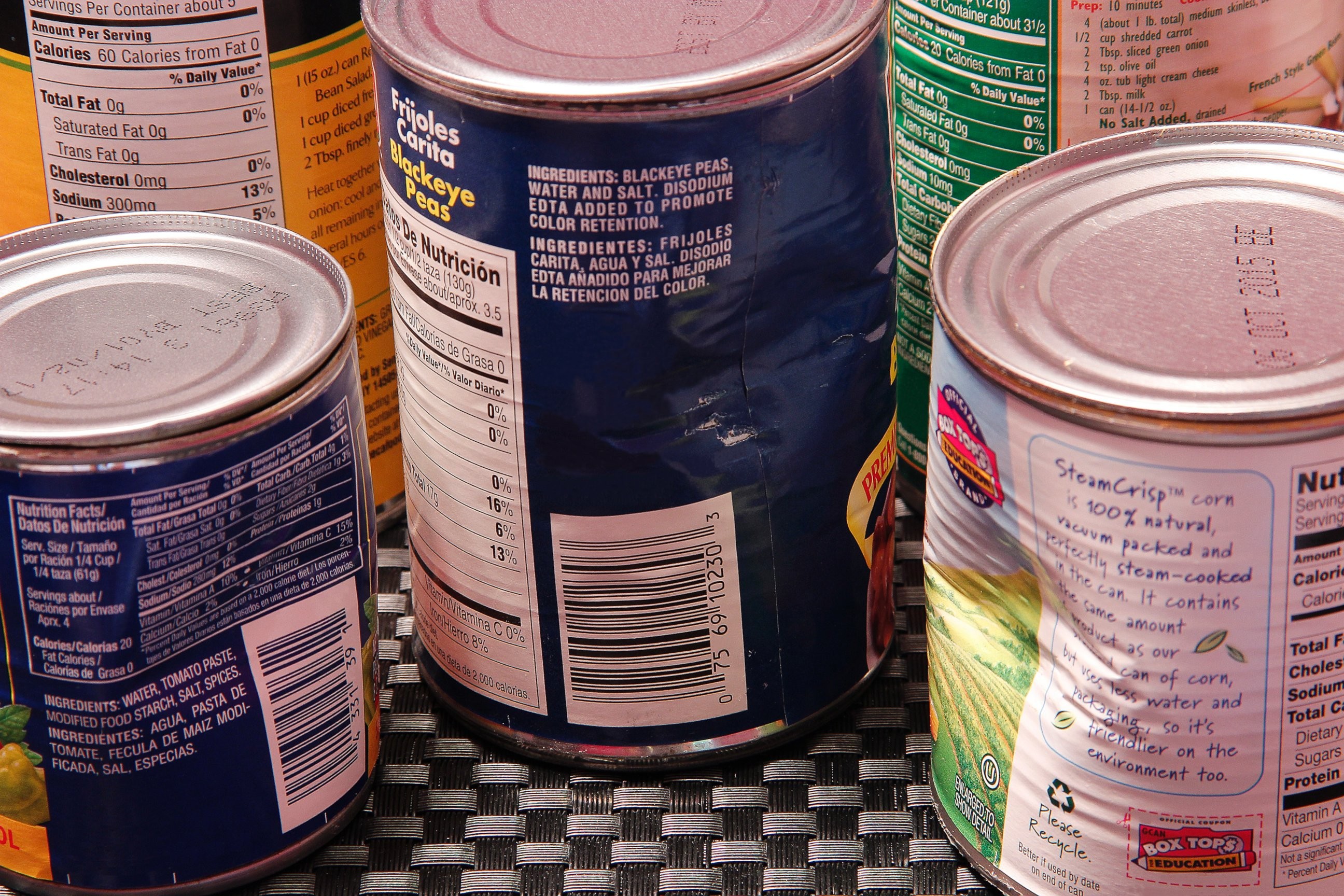 Warning signs of unsafe canned food include dents, cracks, and bulging, indicating potential botulism risk.