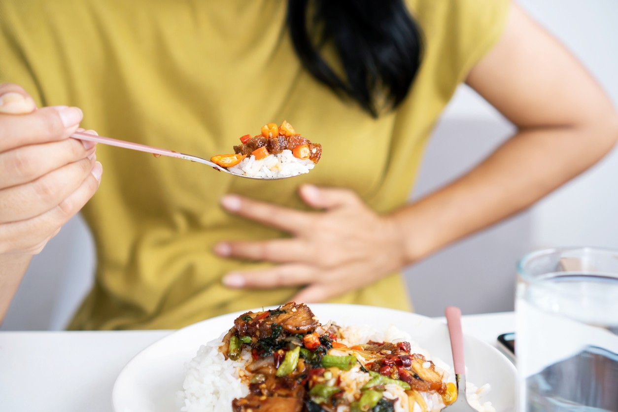 Woman experiencing stomach discomfort after eating spicy food