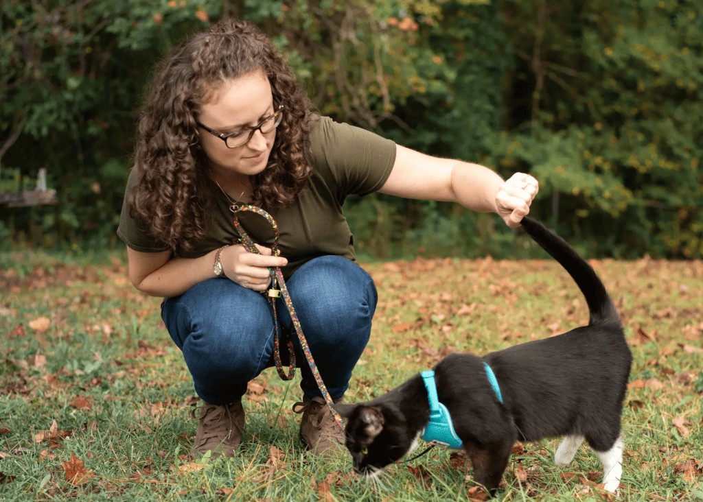 woman with cat outside on a harness and leash