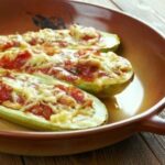 Zucchini halves filled with vegetables and cheese, baked and golden brown, showcasing a family-friendly whole food meal.