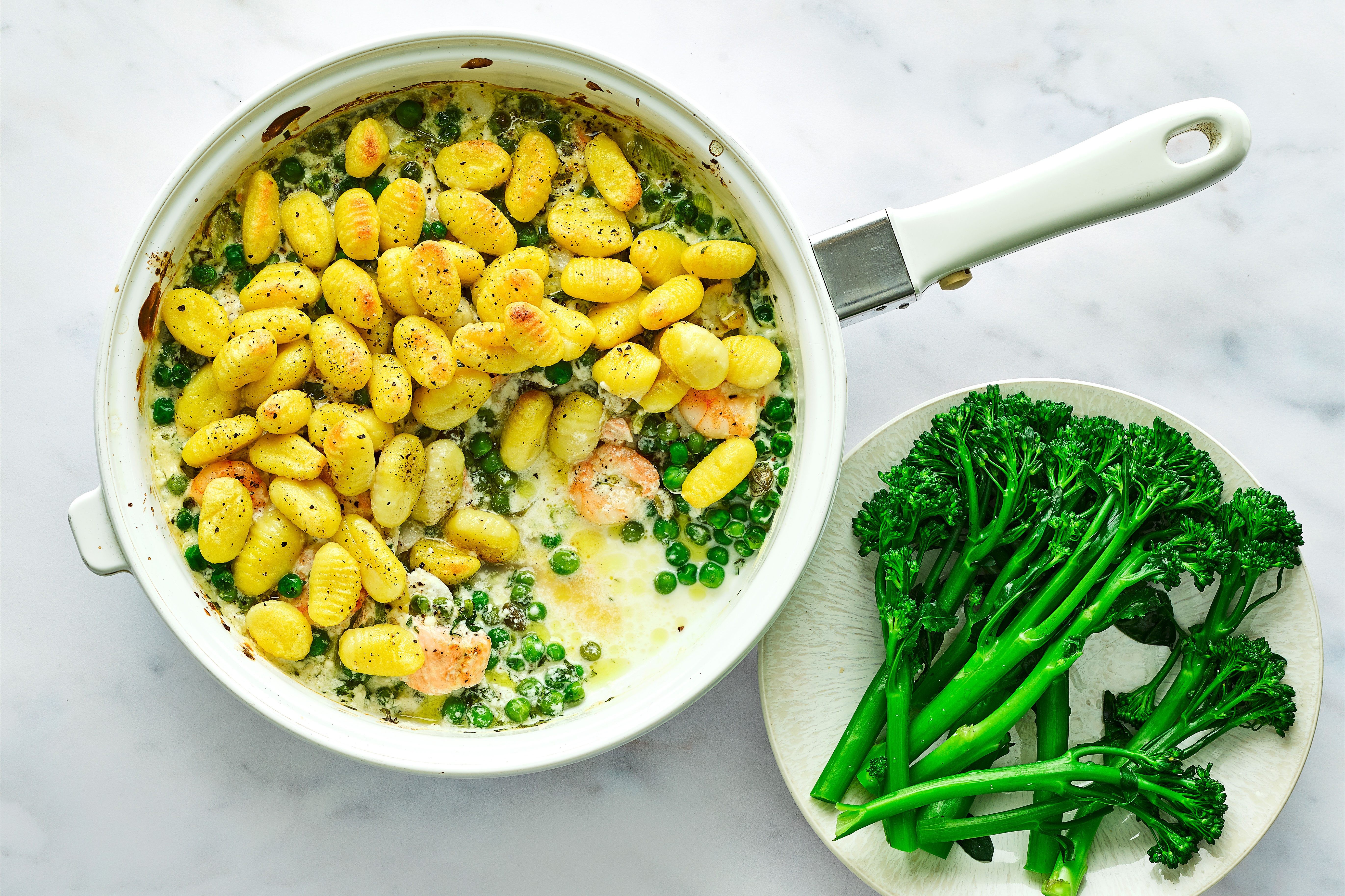Gnocchi fish pie in a pot next to a plate of broccoli