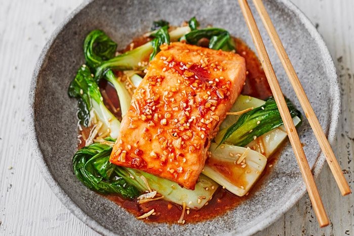 Bowl of teriyaki salmon in a bowl with pak choi and chopsticks