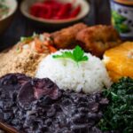 Feijoada, a savory Brazilian black bean and pork stew served with rice, collard greens, farofa and orange slices