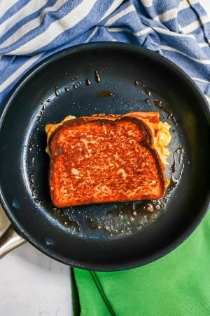 A golden brown breakfast grilled cheese being cooked in a dark skillet, perfect for a quick and easy morning meal