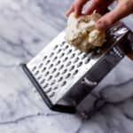 Using a box grater to grate cauliflower.